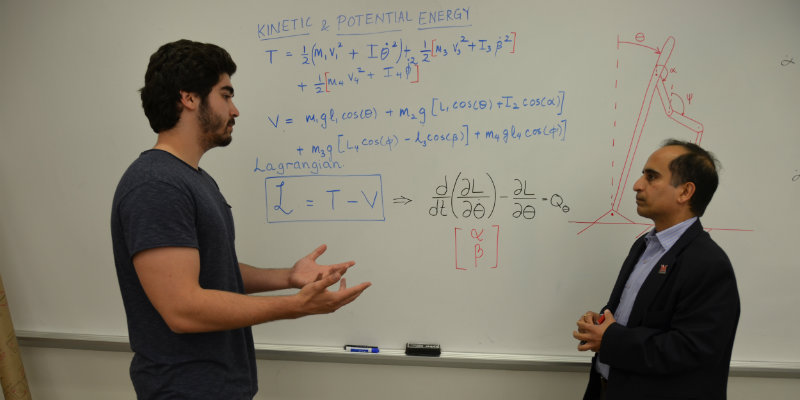 Dr. Shukla and graduate students working on an equation on classroom white board