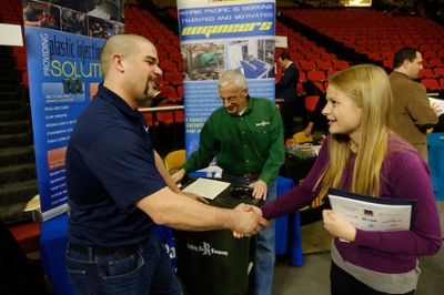 student greeting employer at company booth during a career fair.