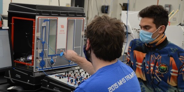Two students in front of a coupled tanks apparatus