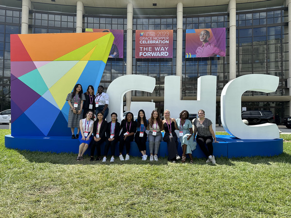 Miami CEC students stand in front of the large GHC23 conference signage in Orlando, Florida
