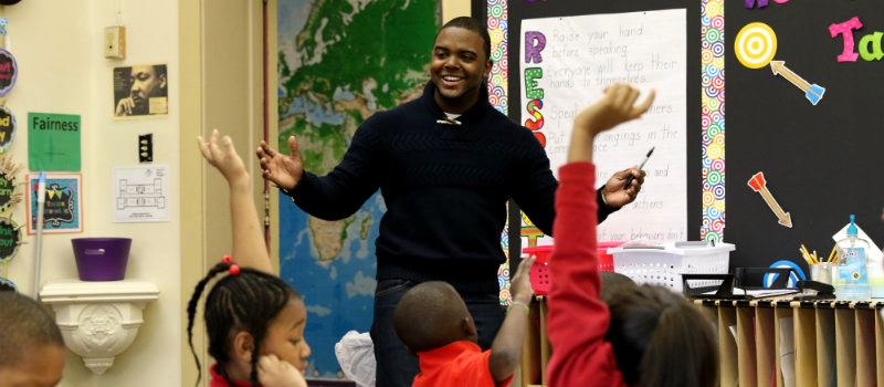 students raising their hands in classroom