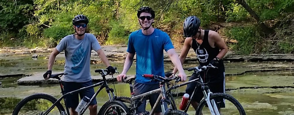 students riding bikes near a small body of water