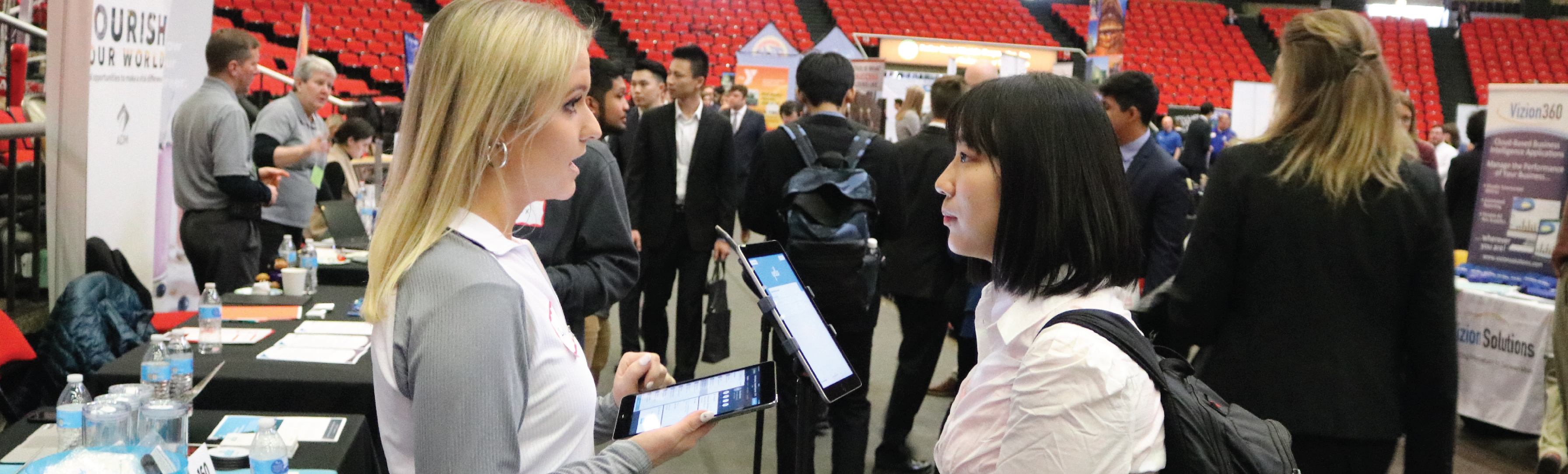 Two people talk to each other in front of a crowd.