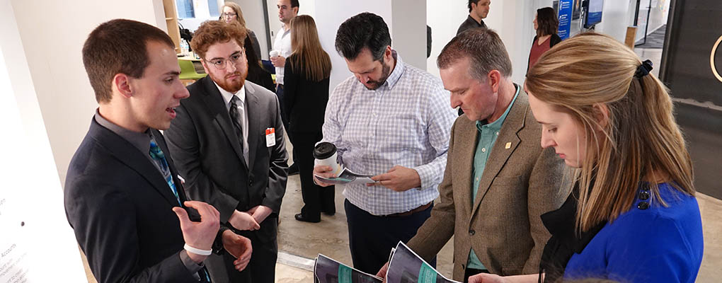 Student talks to visitors at poster presentation
