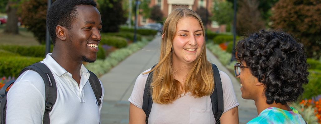 three students chat on the quad
