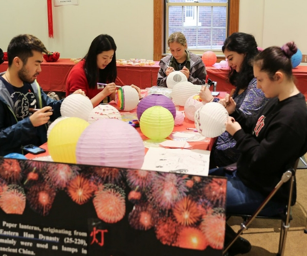 A group of people sit around a table coloring paper lanterns