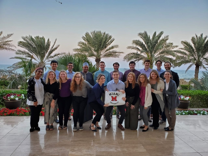 Students pose holding a Miami 'M' flag during a study abroad workshop