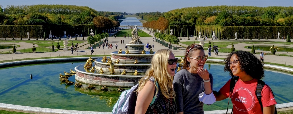 3 student laughing abroad in Paris in front of a fountain outside of Versailles
