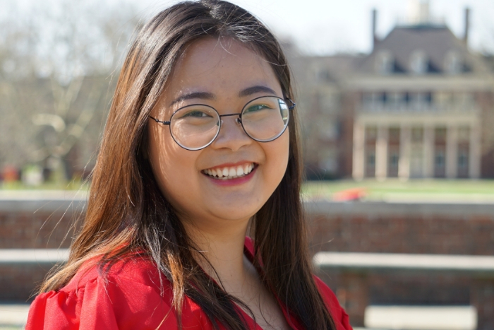 Headshot of Miami alum Sunny (Ni) Suo in front of MacMillan Hall in her red gown for graduation