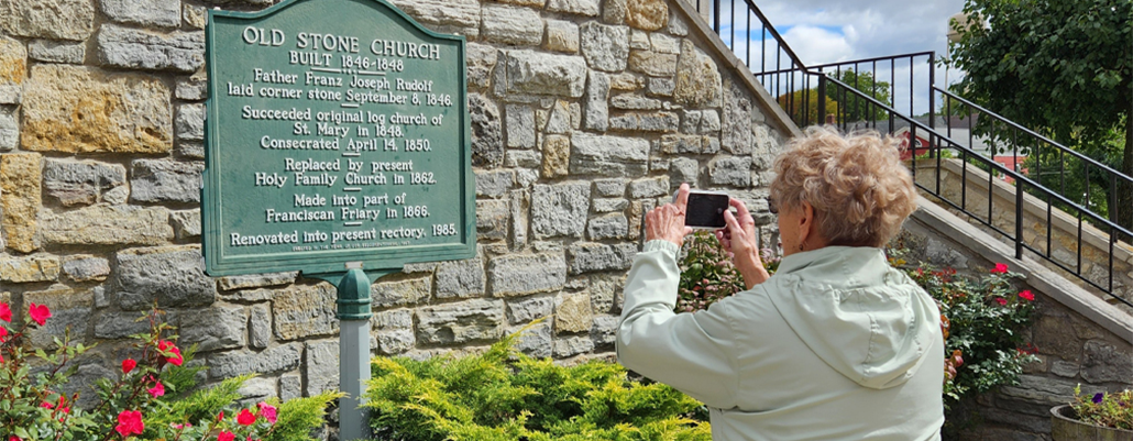 A student faces away as she takes a photo of a historical marker 