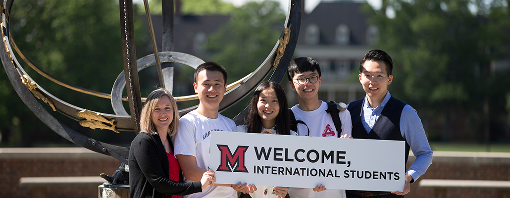 Staff and students hold a sign to welcome international students