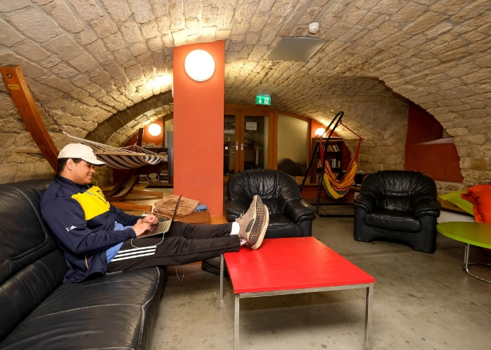 student studying in cave of MUDEC with feet up on table