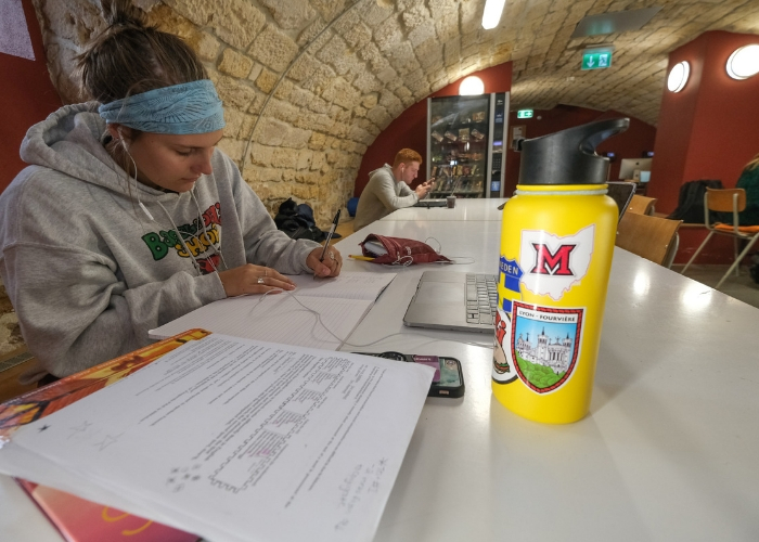 student studying in cave of MUDEC with Bagel and Deli sweatshirt on
