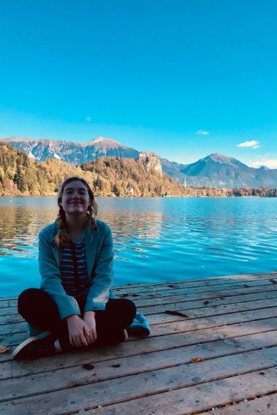 Megan sitting on a dock in front of a beautiful blue body of water in Slovenia