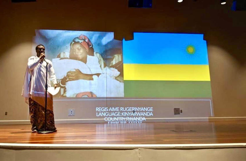 Regis gives a presentation onstage, with a slide showing Rwanda in the background