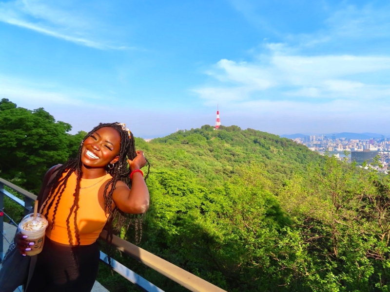Sinait poses near an overlook, Namsan Tower visible in the distance