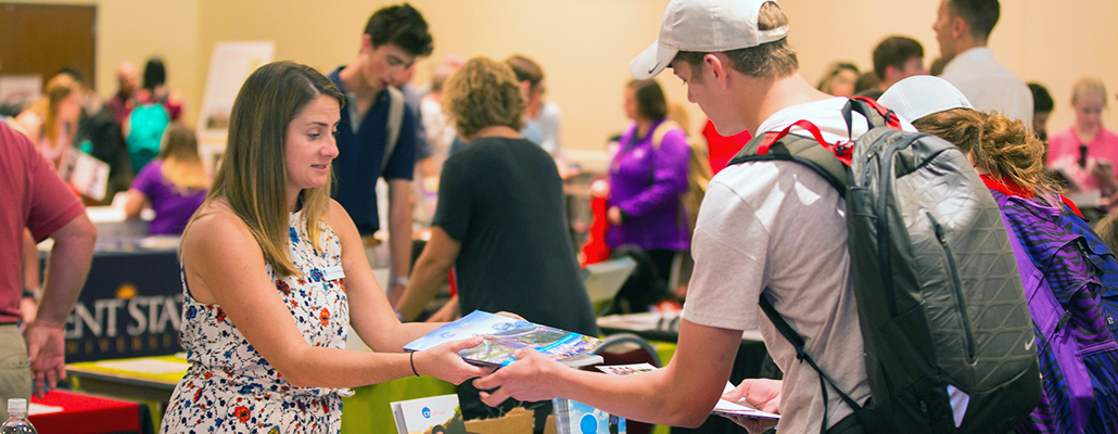  A woman hands out materials to a student at a past study abroad fair