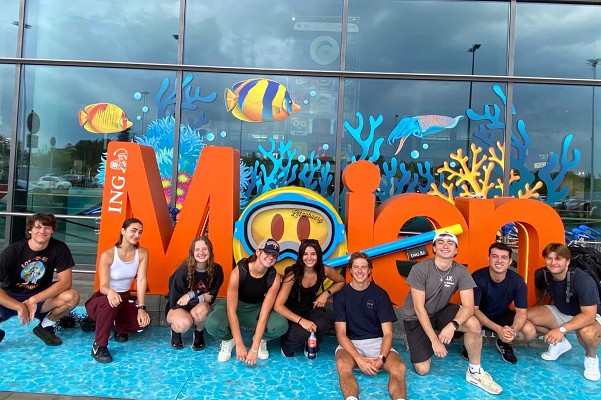 A group of study abroad students posing in front of an aquarium