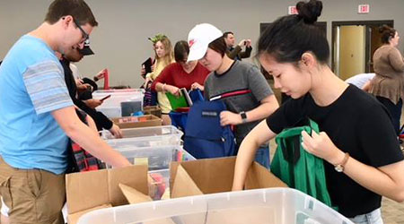 Students working to stuff bags full of school supplies for students. 