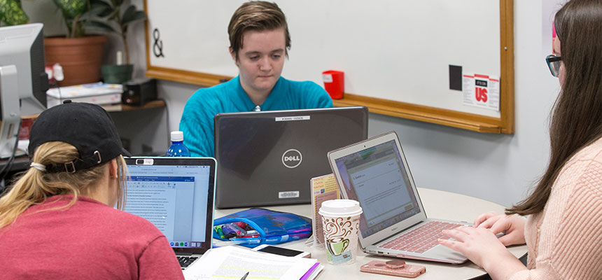 A group of students working on homework at a table in the tutoring and learning center.