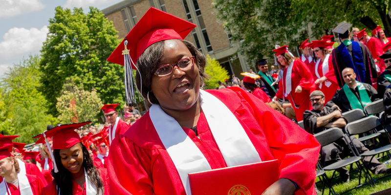 A female TRIO grad smiling after receiving her diploma.