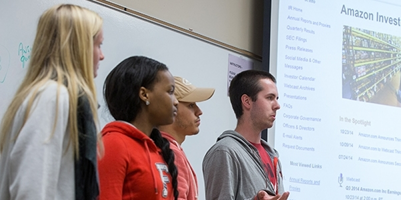 Students standing in a line in the front of the classroom giving a presentation.