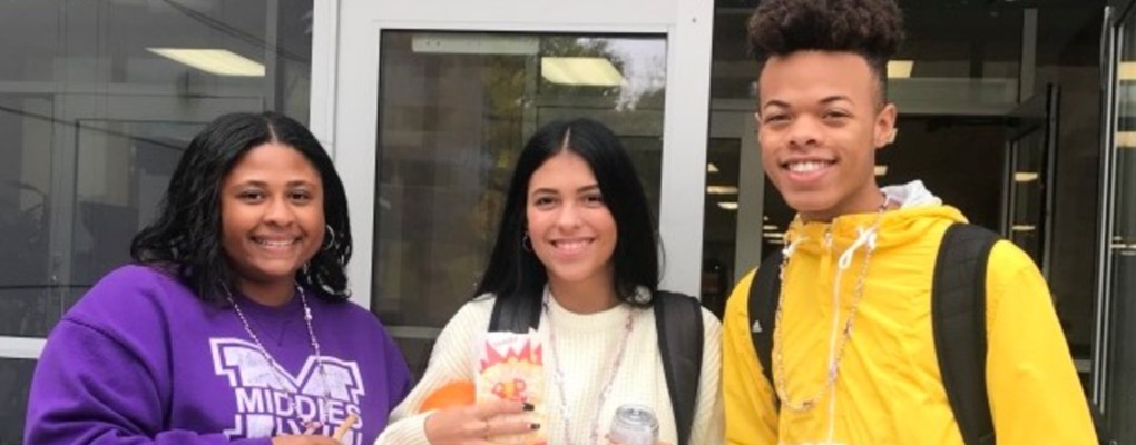 3 students standing outside smiling