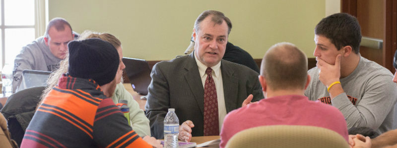 Professor Daniel Hall working at a table with students.