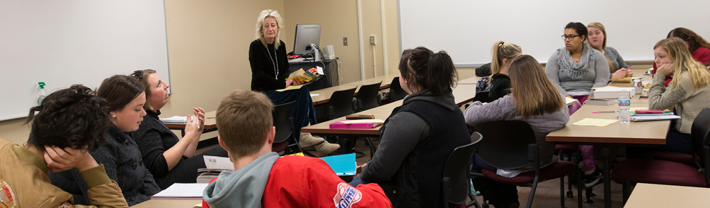 Professor Diana Royer standing in the front of the classroom teaching to her students.