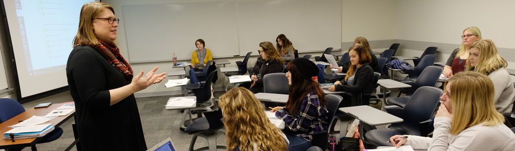 Professor Whitney Womack-Smith standing in the front of the room teaching her class.