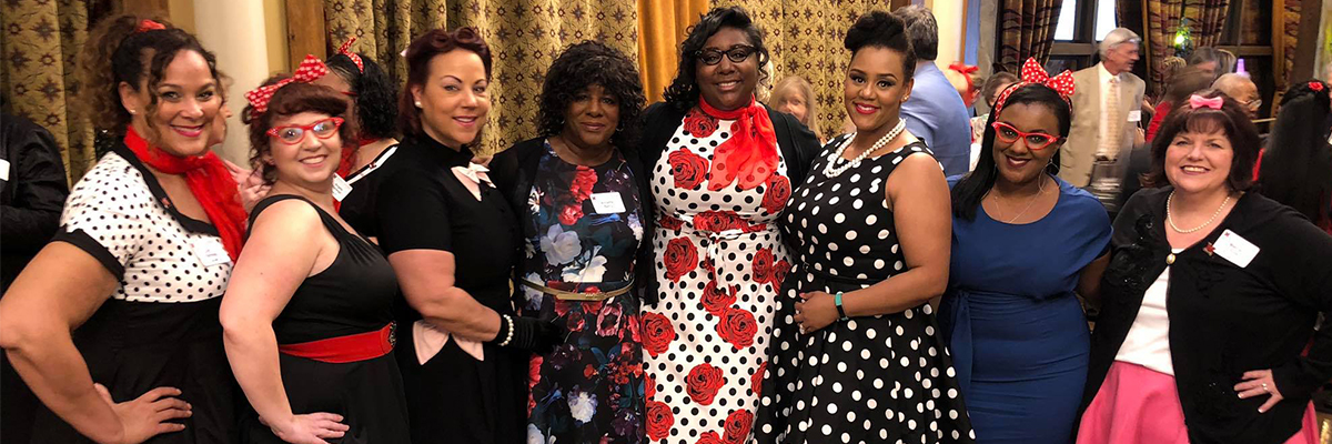 A group of people during the nursing alumni dinner dressed in 60s clothes.