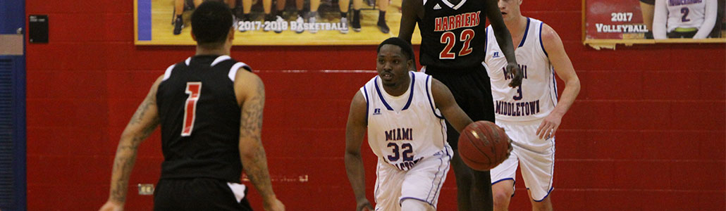 Men's basketball player dribbling down the court with a defender in front of him.