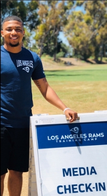 A'mon Yisreal standing next to a way finding sign for Rams Media Day.