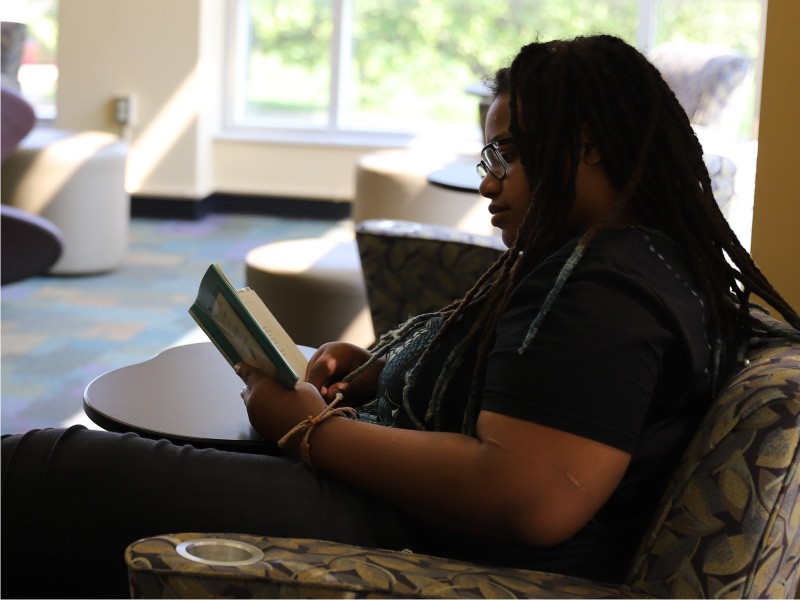Student sitting in the library reading a book.