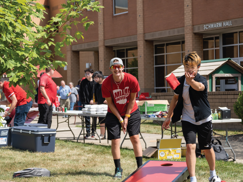 2 students playing corn hole in the Hamilton quad.