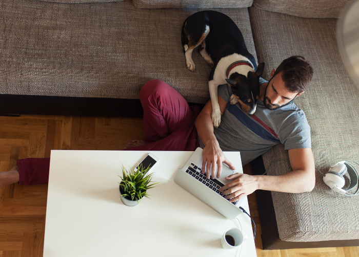 man working on a laptop at home with his dog