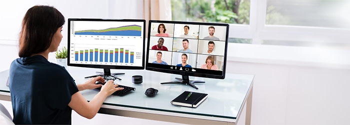 Woman on a video conference viewing participants and charts on different monitors