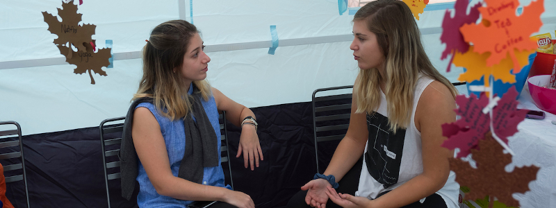 Students chat while sitting in a sukkah