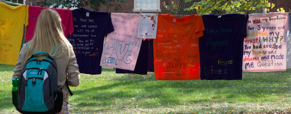 t-shirts strung on a clothesline in academic quad with messages about sexual assault on the shirts. 