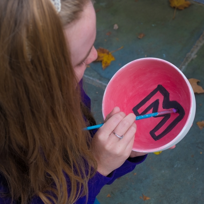  Student painting a Miami M logo in a pottery bowl