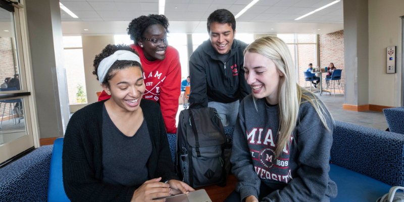 four students around a laptop