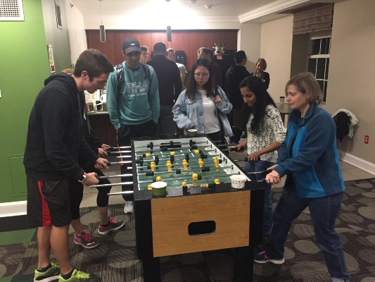people playing foosball with other people conversing in the background