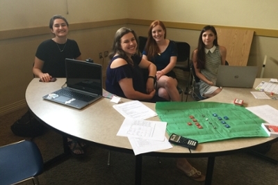  Students from EDL290 Table Top Games and Leadership at an Expo table with a student-created game on the table
