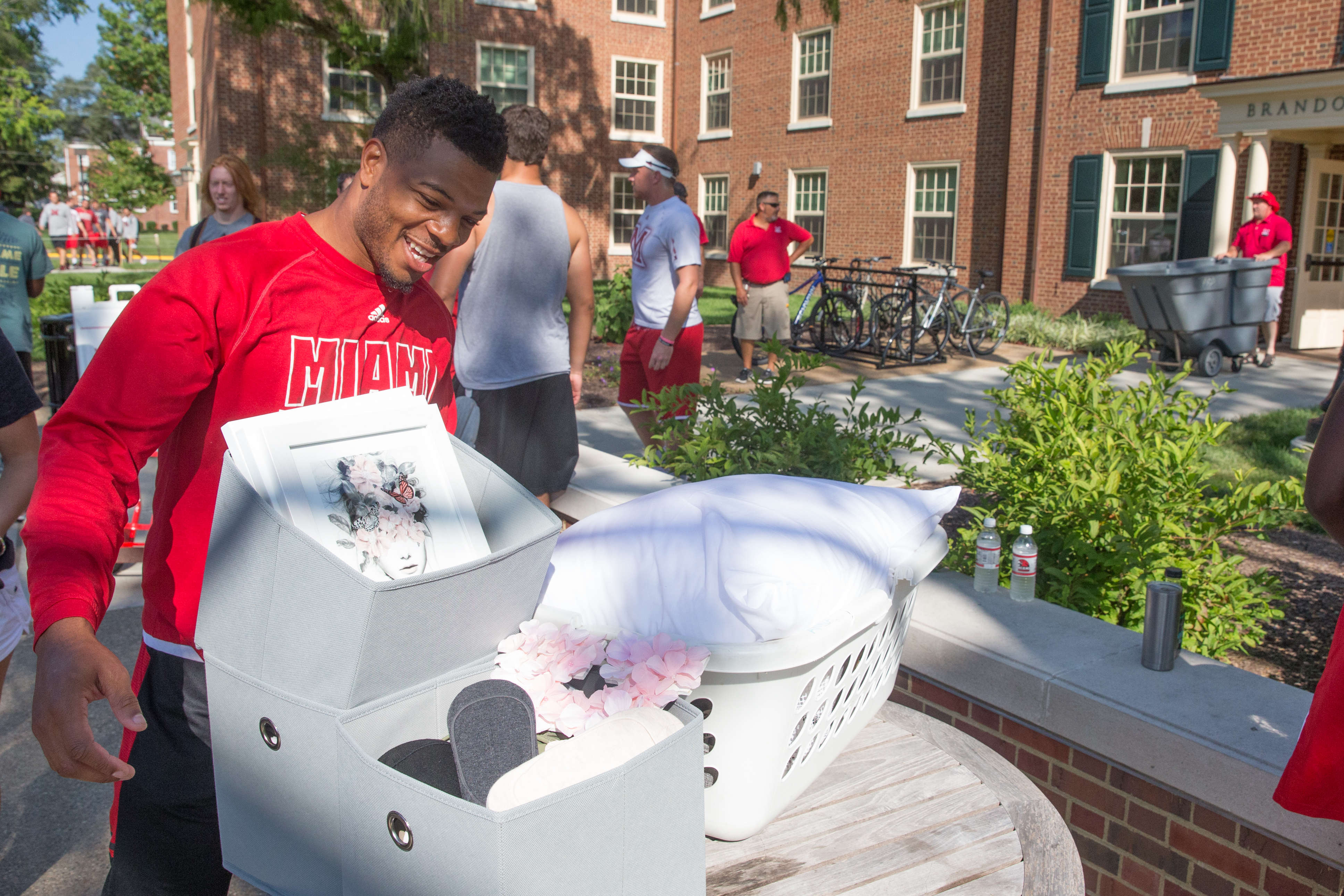  Student in Miami shirt collecting items on a table to help a student move in to the residence halls