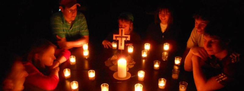  Students gathered in the dark around a cross and votive candles