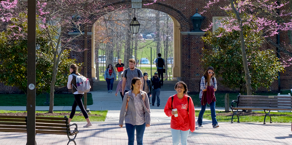 Students walking past the seal and walking under the Upham Arch 
