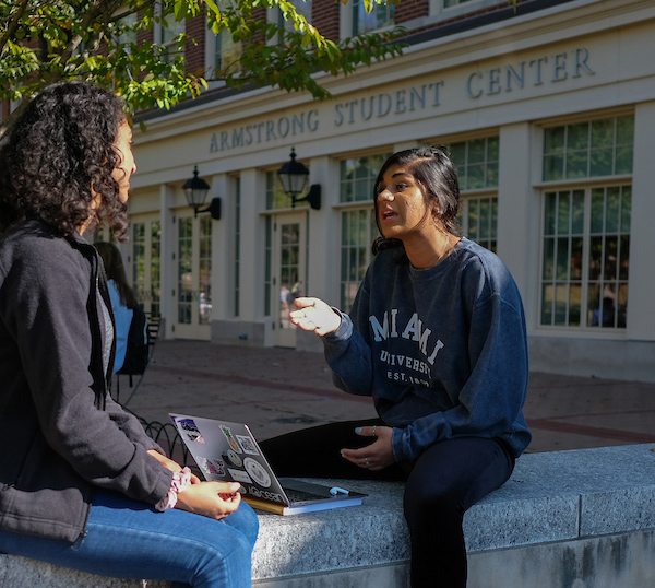 Two students converse on the patio of Armstrong Student Center