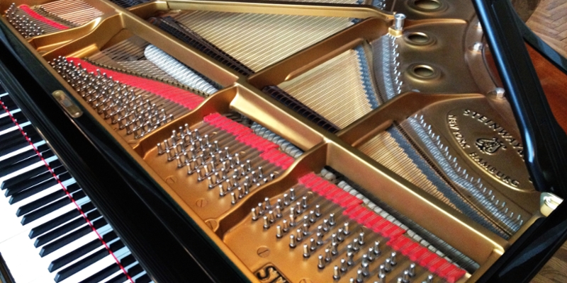 Interior of a Steinway grand piano with strings and hammers that create the sound