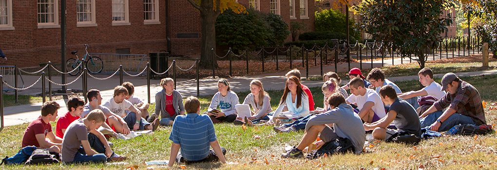 A professor leading a class sitting in a circle outside
