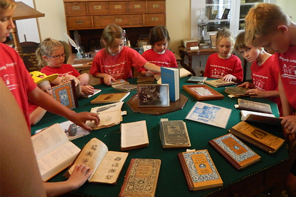 Children examine a selection of McGuffey Readers arrayed on McGuffey's famous green octagonal table
